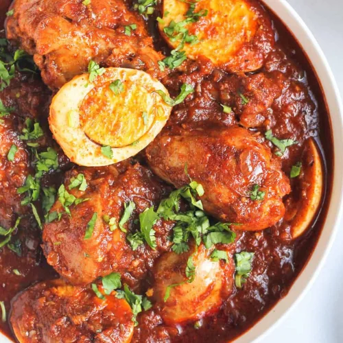 Doro Wot - Ethiopia's beloved chicken stew slow-cooked in a rich berbere spice sauce, served with a hard-boiled egg and spongy injera bread.